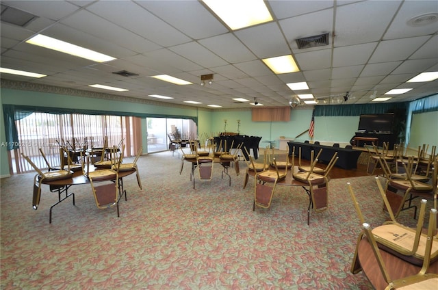 carpeted dining area featuring a drop ceiling