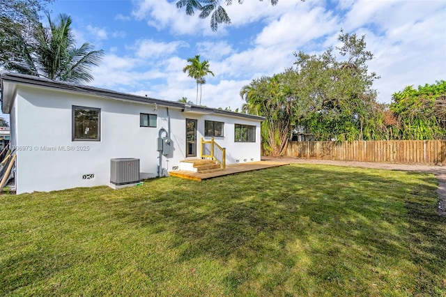 rear view of property with cooling unit and a lawn