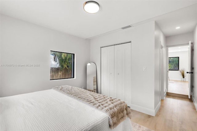 bedroom with light hardwood / wood-style floors and a closet