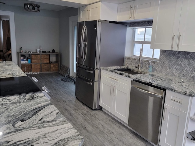 kitchen with white cabinets, light wood-type flooring, and appliances with stainless steel finishes