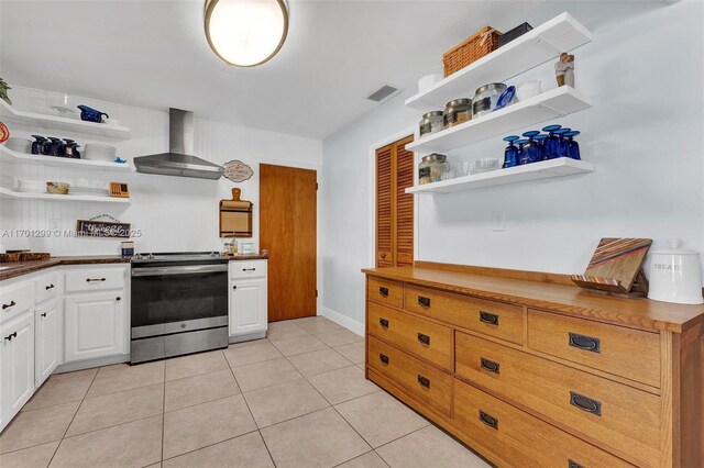 kitchen featuring white cabinetry, wall chimney exhaust hood, light tile patterned floors, and stainless steel range with electric cooktop