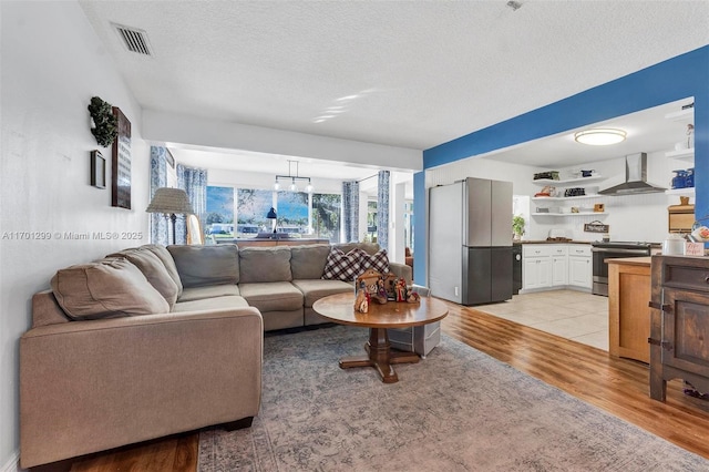 living room featuring light hardwood / wood-style floors, a chandelier, and a textured ceiling