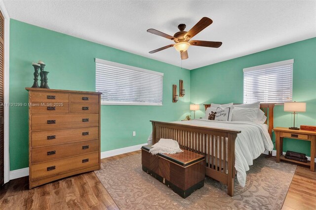 bedroom featuring ceiling fan, wood-type flooring, and a textured ceiling