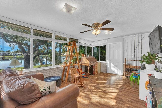 sunroom / solarium featuring ceiling fan and a water view