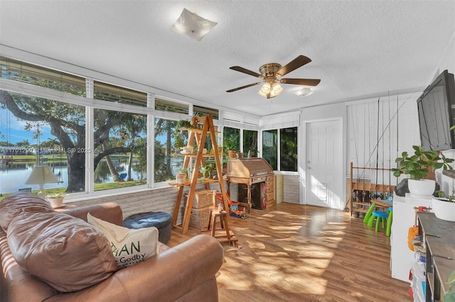 sunroom / solarium with ceiling fan and a water view