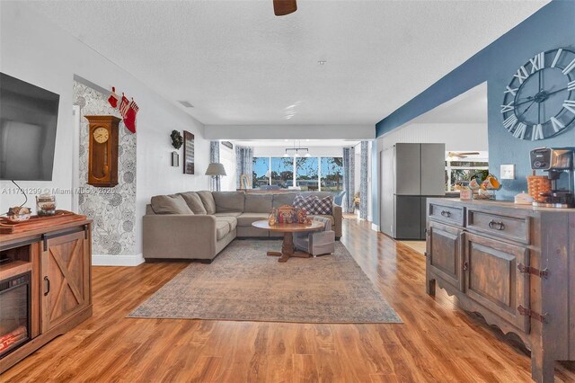 living room with a healthy amount of sunlight, light hardwood / wood-style floors, a textured ceiling, and an inviting chandelier