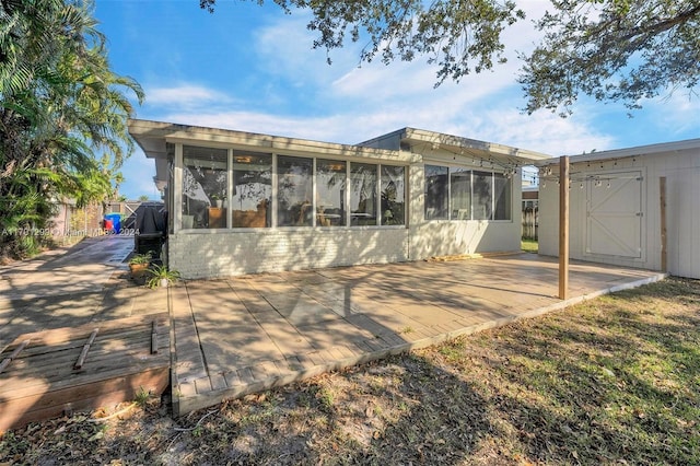 rear view of property featuring a patio area, a sunroom, and a storage unit