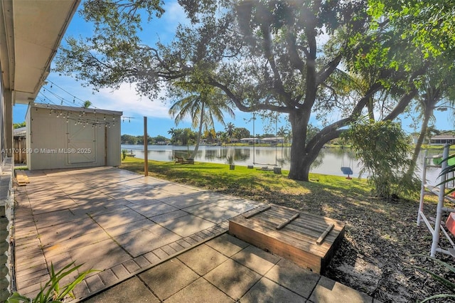 view of patio with a water view and a shed