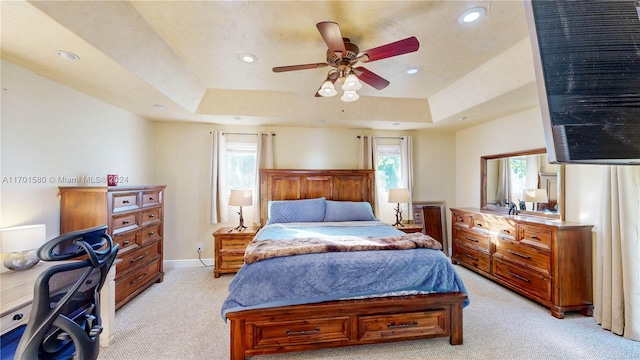 carpeted bedroom with a tray ceiling and ceiling fan