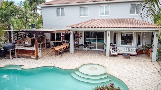 back of house featuring an outdoor pool, a tiled roof, outdoor lounge area, and a patio