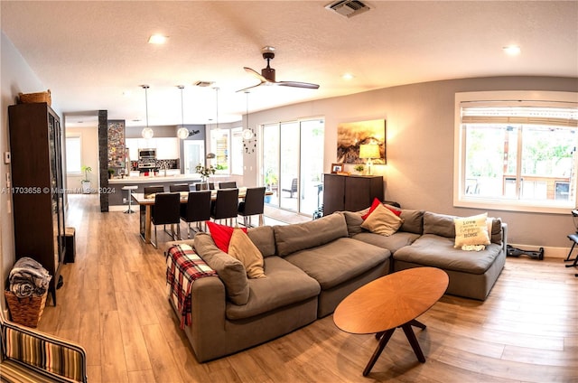 living room with a textured ceiling, light hardwood / wood-style floors, and ceiling fan