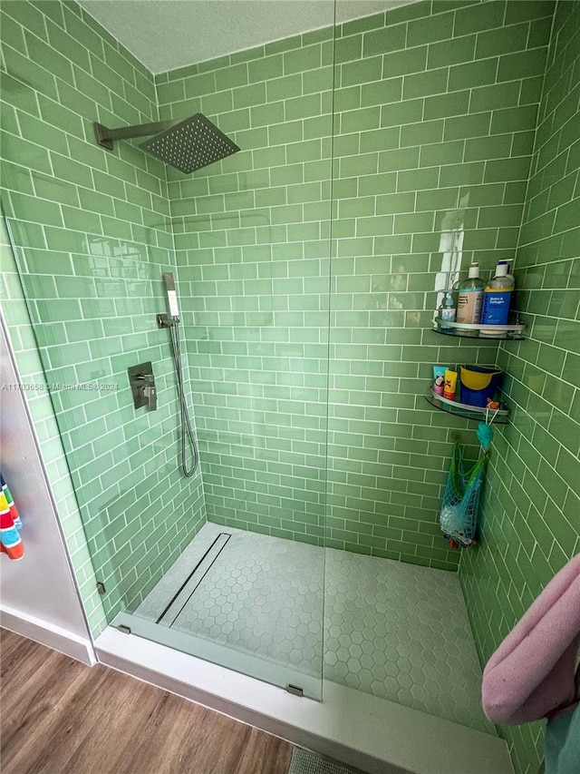 bathroom featuring a tile shower and wood-type flooring