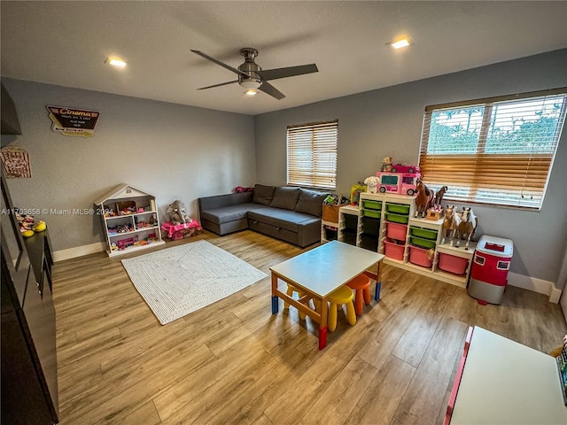 playroom with ceiling fan, light hardwood / wood-style flooring, and a healthy amount of sunlight