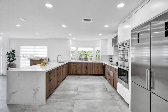 kitchen with kitchen peninsula, backsplash, stainless steel appliances, and white cabinetry