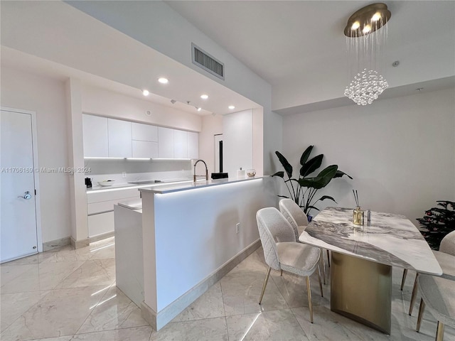 kitchen featuring pendant lighting, sink, white cabinetry, and kitchen peninsula