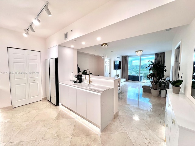 1755 E Hallandale Beach Blvd Unit 405E, Hallandale Beach, FL 33009 - kitchen with white cabinetry, light marble finish flooring, a peninsula, and light countertops