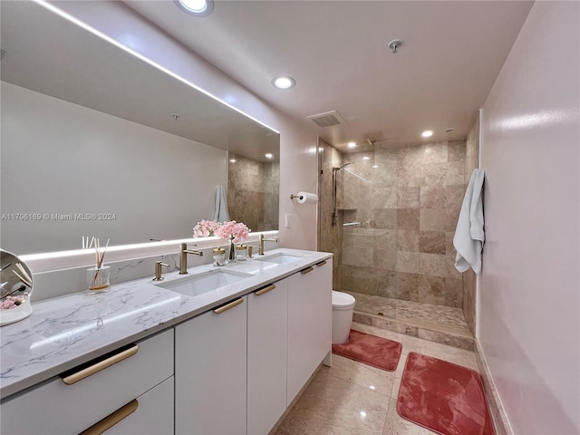 bathroom featuring tile patterned flooring, vanity, toilet, and a tile shower