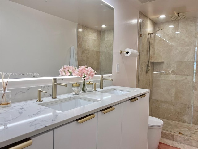 bathroom with toilet, vanity, and tiled shower