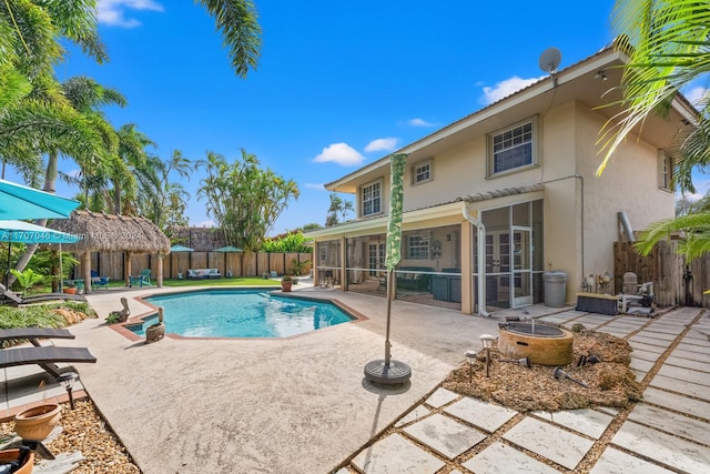 view of swimming pool featuring a patio area, a sunroom, and an outdoor fire pit