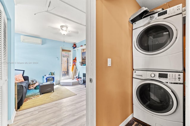 laundry area featuring a wall mounted AC, light hardwood / wood-style floors, stacked washer / dryer, and ceiling fan