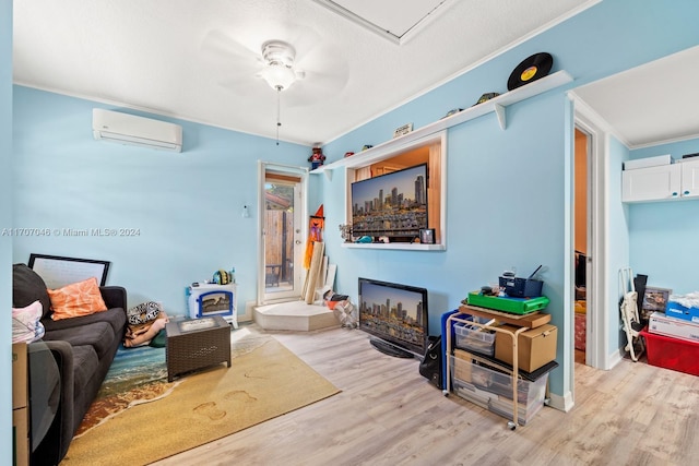 living room with a wall mounted air conditioner, ceiling fan, light wood-type flooring, and ornamental molding