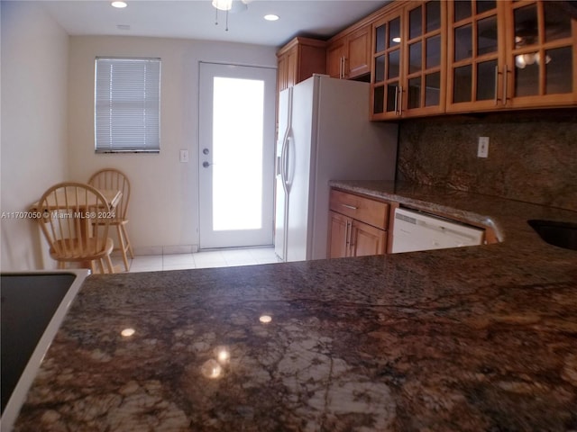 kitchen with ceiling fan, dark stone countertops, white appliances, and tasteful backsplash