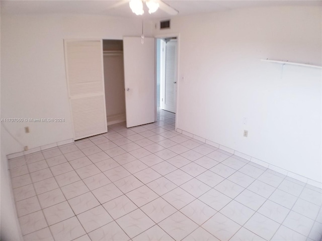 unfurnished bedroom with ceiling fan, a closet, and light tile patterned floors