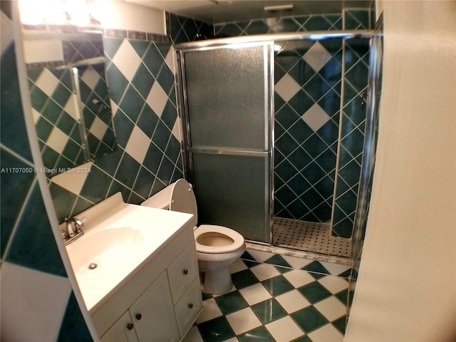 bathroom featuring vanity, toilet, walk in shower, and tile walls