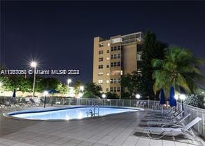 pool at night featuring a patio area