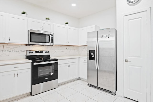 kitchen with white cabinets, decorative backsplash, light tile patterned floors, and stainless steel appliances