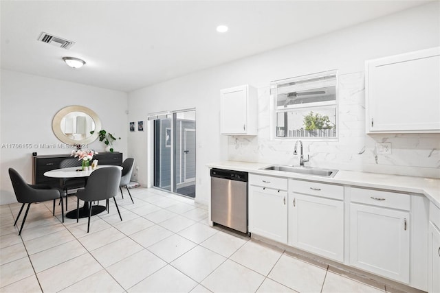 kitchen with stainless steel dishwasher, backsplash, white cabinetry, and sink