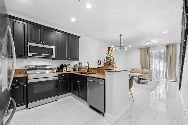 kitchen with sink, hanging light fixtures, a textured ceiling, kitchen peninsula, and stainless steel appliances