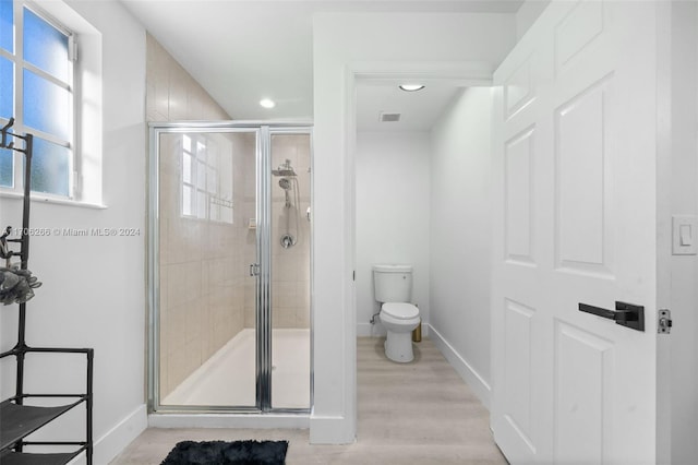 bathroom with hardwood / wood-style floors, toilet, and walk in shower