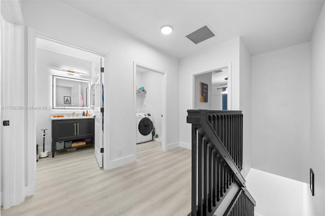 hall with washer / dryer and light hardwood / wood-style flooring