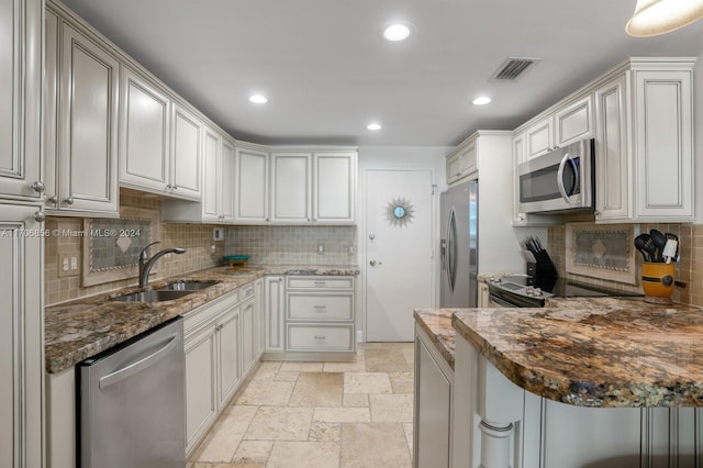 kitchen featuring decorative backsplash, stainless steel appliances, sink, dark stone countertops, and white cabinets