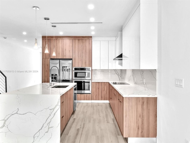 kitchen featuring light stone counters, light hardwood / wood-style floors, decorative light fixtures, white cabinets, and appliances with stainless steel finishes