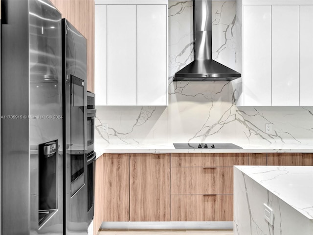 kitchen featuring white cabinets, appliances with stainless steel finishes, light stone countertops, and wall chimney exhaust hood