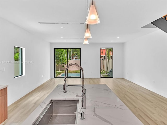 kitchen with light stone countertops, light hardwood / wood-style flooring, and decorative light fixtures