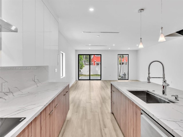 kitchen featuring sink, dishwasher, light stone counters, pendant lighting, and light wood-type flooring