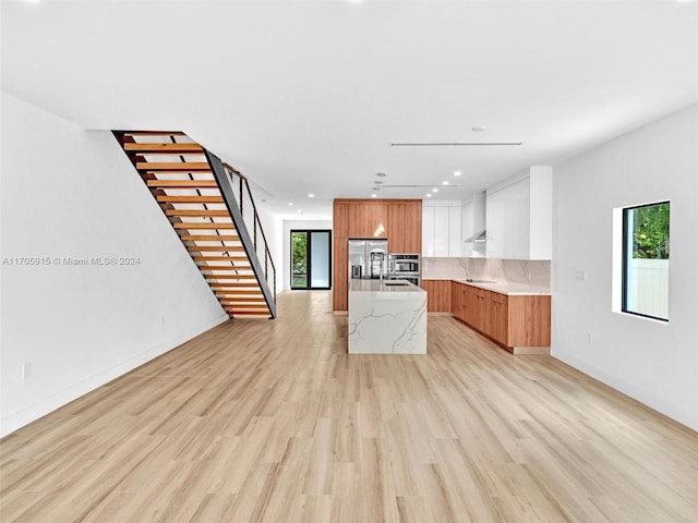 kitchen with white cabinetry, plenty of natural light, an island with sink, and light wood-type flooring