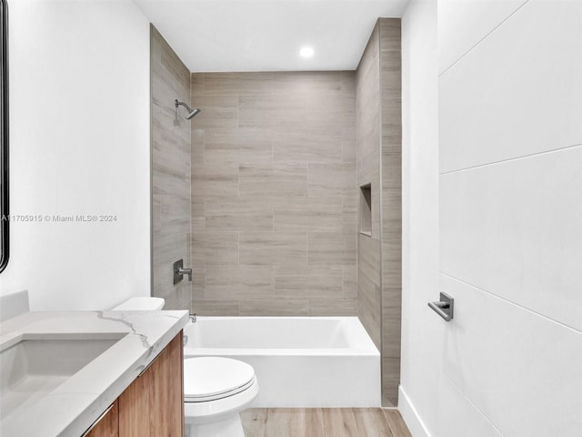 full bathroom featuring vanity, toilet, wood-type flooring, and tiled shower / bath