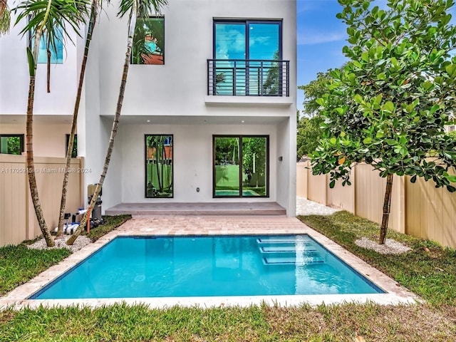 rear view of house with a balcony and a fenced in pool