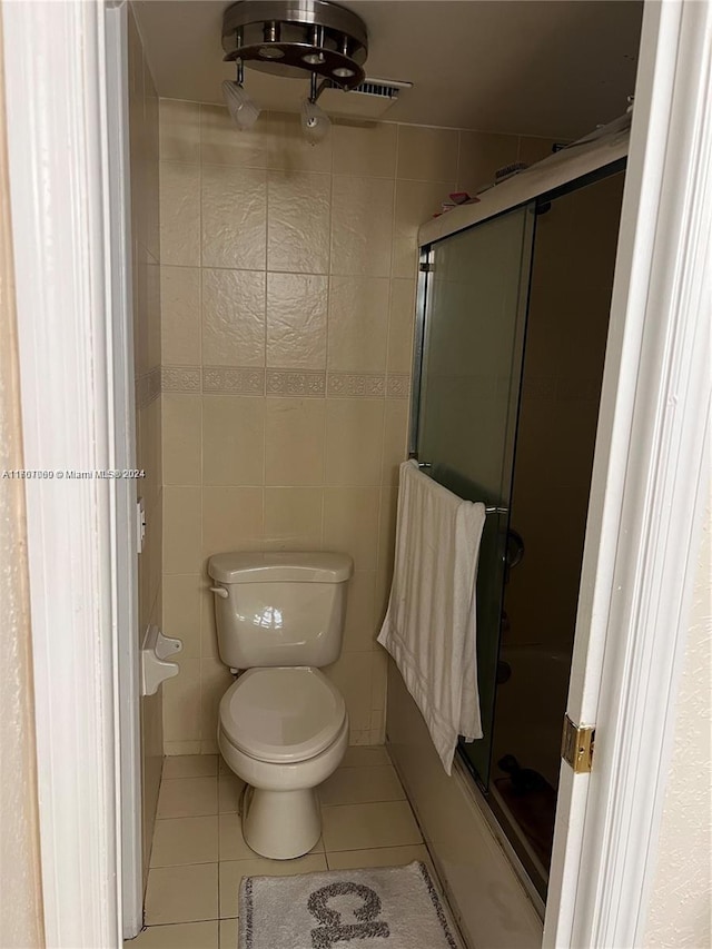 bathroom featuring toilet, tile patterned floors, walk in shower, and tile walls