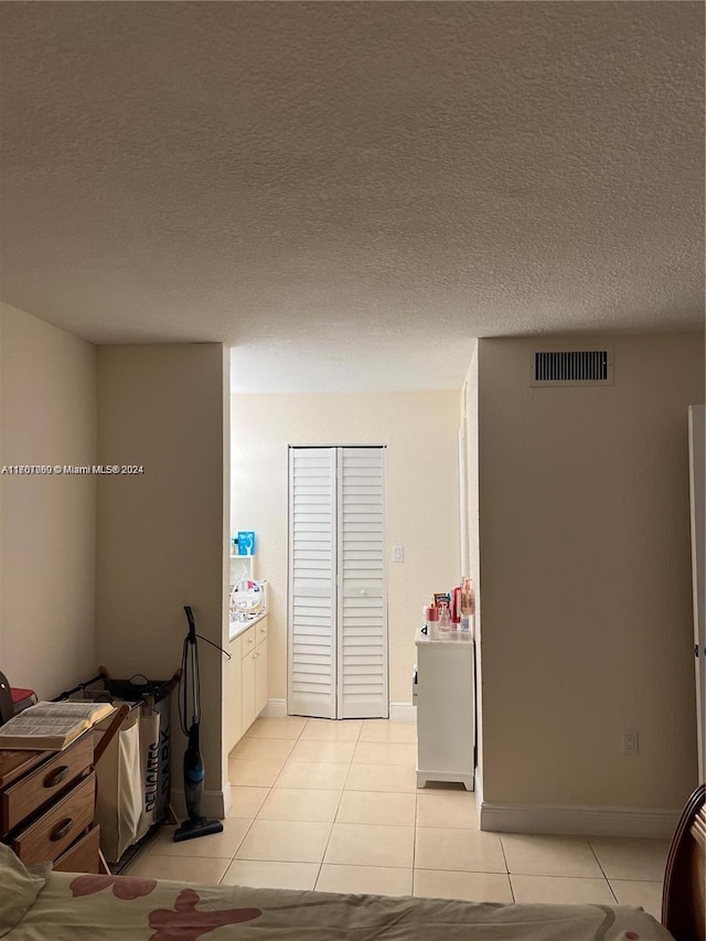 corridor with light tile patterned flooring and a textured ceiling