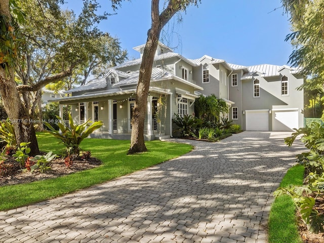 view of front of property featuring covered porch, a front yard, and a garage