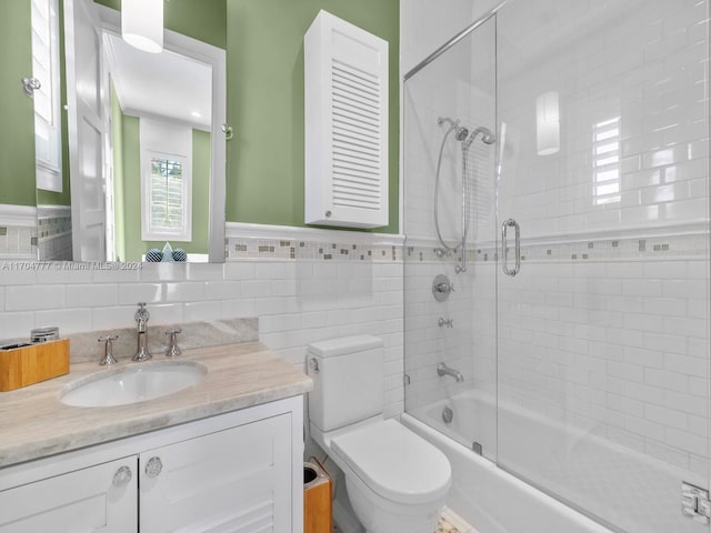 full bathroom with toilet, vanity, tile walls, and combined bath / shower with glass door