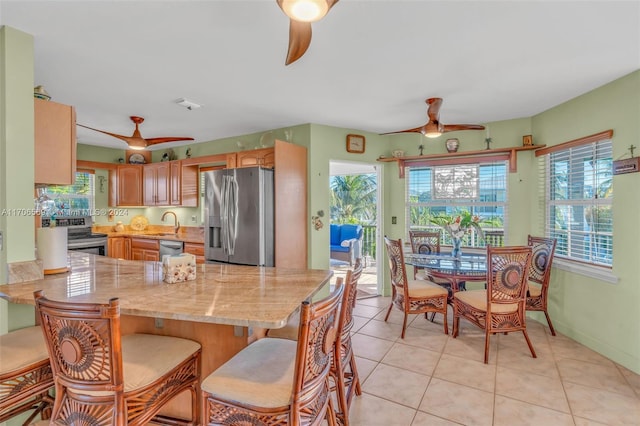 kitchen featuring kitchen peninsula, a kitchen bar, stainless steel appliances, sink, and light tile patterned floors