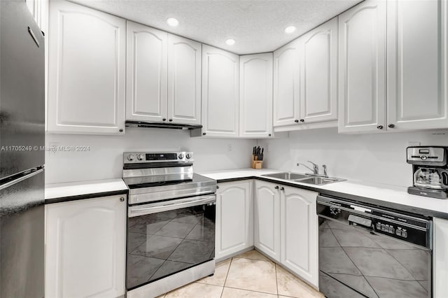 kitchen with appliances with stainless steel finishes, a textured ceiling, sink, light tile patterned floors, and white cabinetry