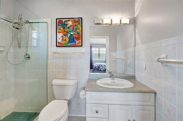 bathroom featuring vanity, toilet, tiled shower, and tile walls