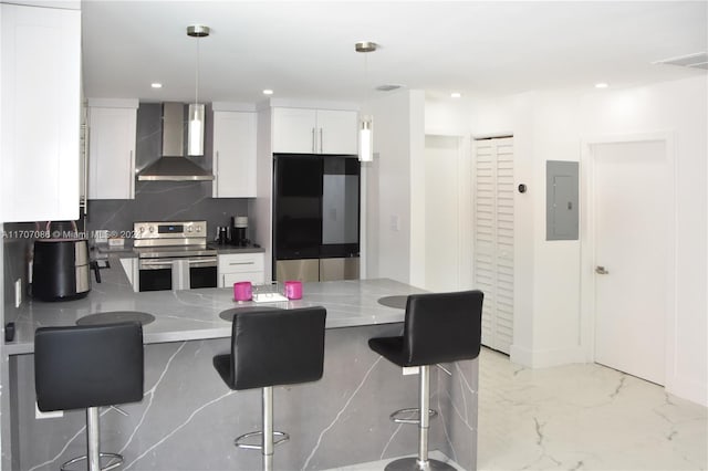 kitchen featuring hanging light fixtures, stainless steel appliances, wall chimney range hood, a breakfast bar area, and white cabinets